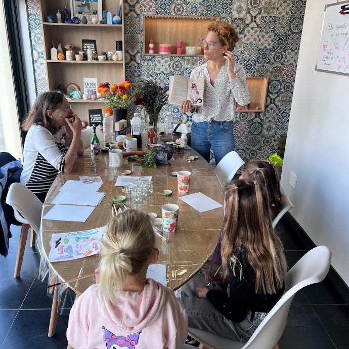 Femme présentant des activités créatives à un groupe d'enfants autour d'une table.