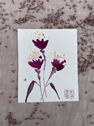 Trois fleurs violettes avec des pétales dorés sur fond clair.