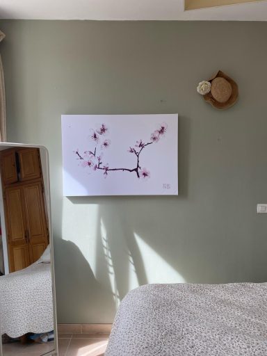Tableau de fleurs de cerisier sur un mur vert, avec une décoration murale ronde.