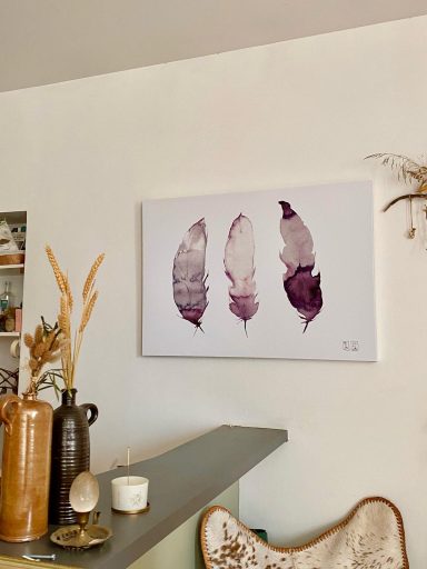 Trois plumes violettes sur toile, accrochées au mur, décor artistique minimaliste.