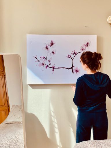 Une personne regarde un tableau représentant une branche de cerisier en fleurs.
