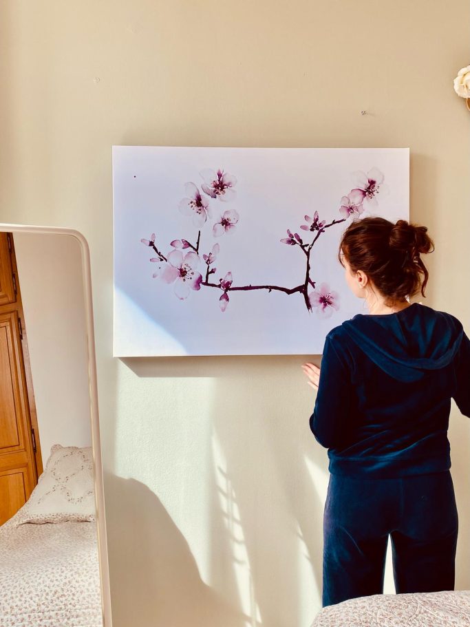 Une personne regarde un tableau représentant une branche de cerisier en fleurs.